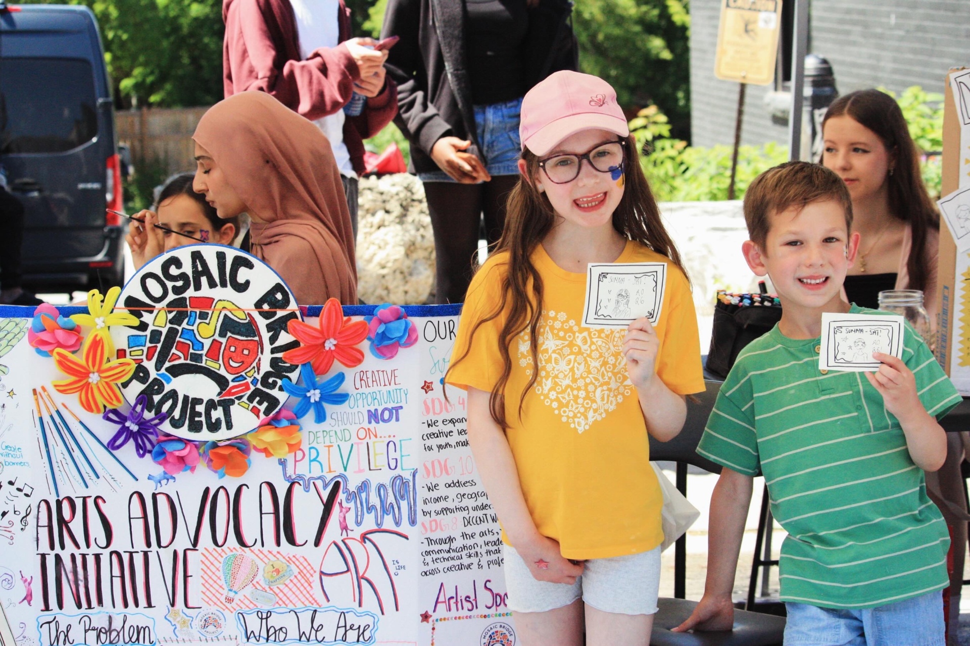 Young visitors showing off their face paint and doodle-booth art.